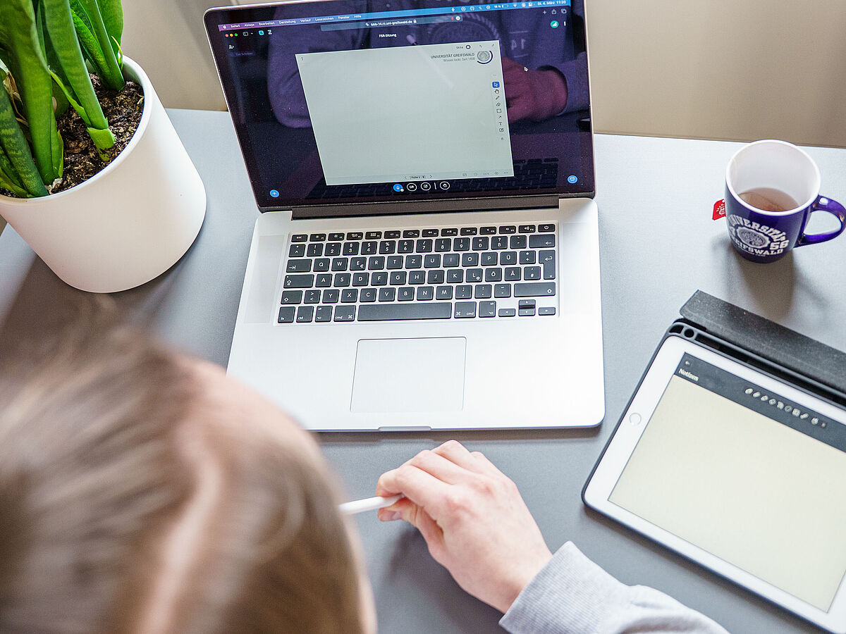 Eine Person sitzt vor einem geöffneten Laptop in einem Online-Meeting.