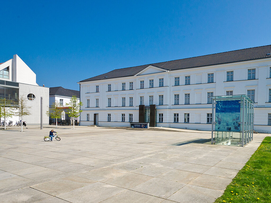 Das Pommersche Landesmuseum in Greifswald Blick auf das Pommersche Landesmuseum in Greifswald; auf dem Platz davor fährt ein kleiner Junge mit dem Fahrrad.