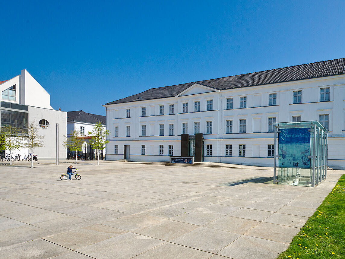 Das Pommersche Landesmuseum in Greifswald Blick auf das Pommersche Landesmuseum in Greifswald; auf dem Platz davor fährt ein kleiner Junge mit dem Fahrrad.