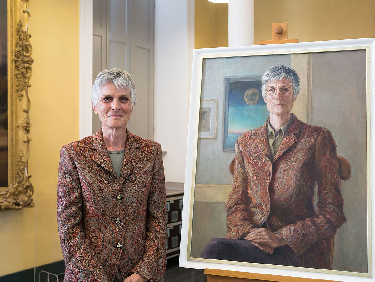 Prof. Dr. Johanna Weber vor ihrem Ölporträt, das die Künstlerin Katrin Lau schuf.
