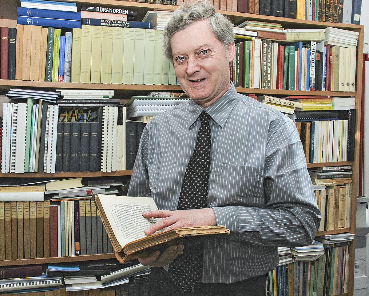 Prof. Dr. Jens E. Olesen steht vor einer großen Bücherwand.