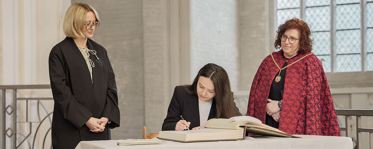 A young woman signing the University's guest book in the cathedral.