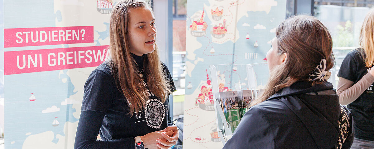 Eine Campusspezialistin stellt einer Besucherin die Studienangebote der Uni Greifswald vor.