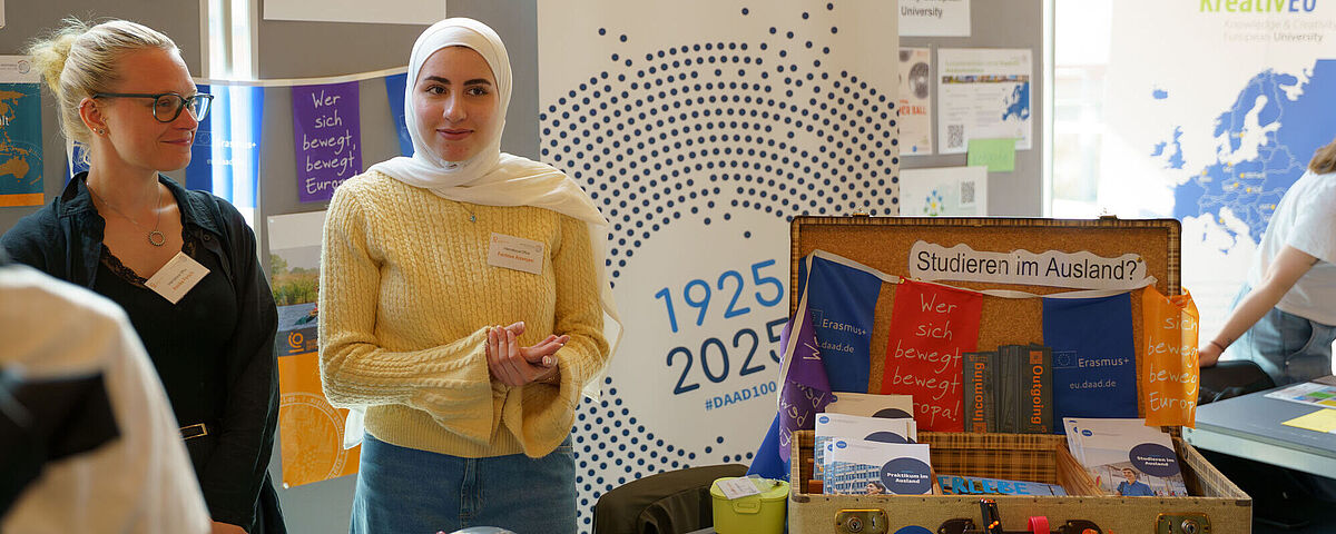 Zwei Frauen stehen bei den Hochschulinfotagen am Stand des International Office.
