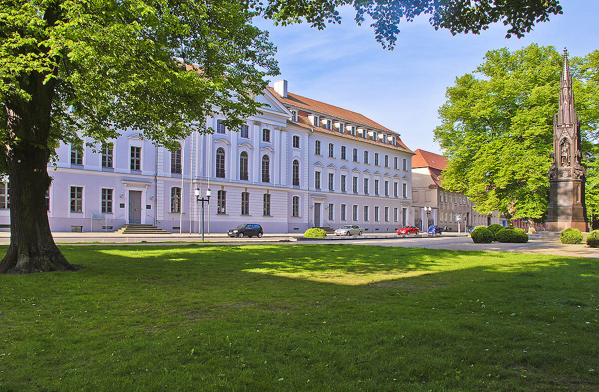 Hauptgebäude der Universität Greifswald Straßenansicht vom Hauptgebäude der Universität Greifswald. Davor liegt der Rubenowplatz mit seinen grünen Bäumen und der großen Wiese.